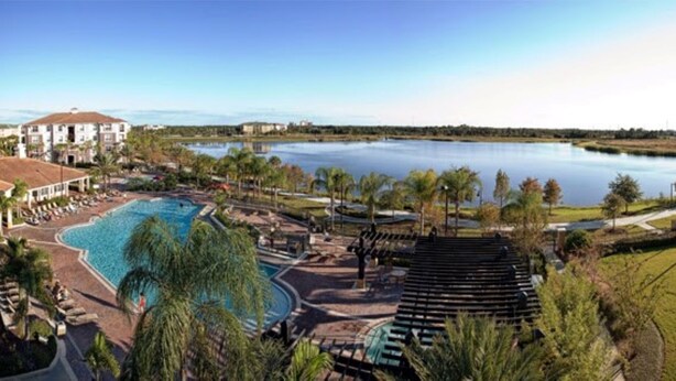 A resort with a large swimming pool, a stage, and a view of a lake. - Vista Cay Resort Townhome near Convention/Universal/SeaWorld/Single Greek Golf (Orlando)