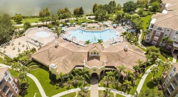 A resort with a central swimming pool, multiple lounge areas, and a well-maintained garden.