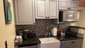 A compact kitchen with white cabinets, a stainless steel microwave, a coffee maker, and a kettle. - Romantic Retreat for Two: Make A Montana Memory! (Livingston)