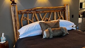 A bed with a wooden headboard, two wall-mounted lights, and a bedside table with a tissue box. - Romantic Retreat for Two: Make A Montana Memory! (Livingston)