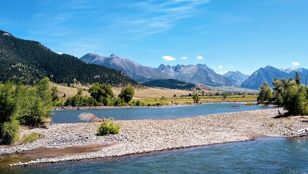 A river with rocky banks and a mountainous backdrop. - Romantic Retreat for Two: Make A Montana Memory! (Livingston)