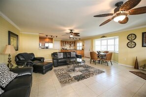 Relax in this stylish living area with a sofa, coffee table, and dining table, surrounded by natural light and a fully equipped kitchen.