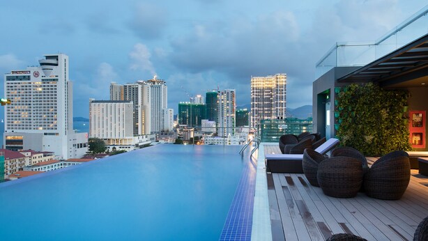 A rooftop infinity pool with a city view, lounge chairs, and a glass railing. - Sao Viet Hotel (Nha Trang)
