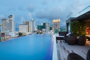 A rooftop infinity pool with a city view, lounge chairs, and a glass railing. - Sao Viet Hotel (Nha Trang)