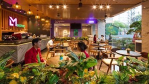 A restaurant with a wooden ceiling, indoor plants, and a bar area with a neon sign. - Sao Viet Hotel (Nha Trang)