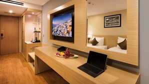 A modern hotel room with a wooden desk, a laptop, a flat-screen TV, and a bed with pillows. - Sao Viet Hotel (Nha Trang)