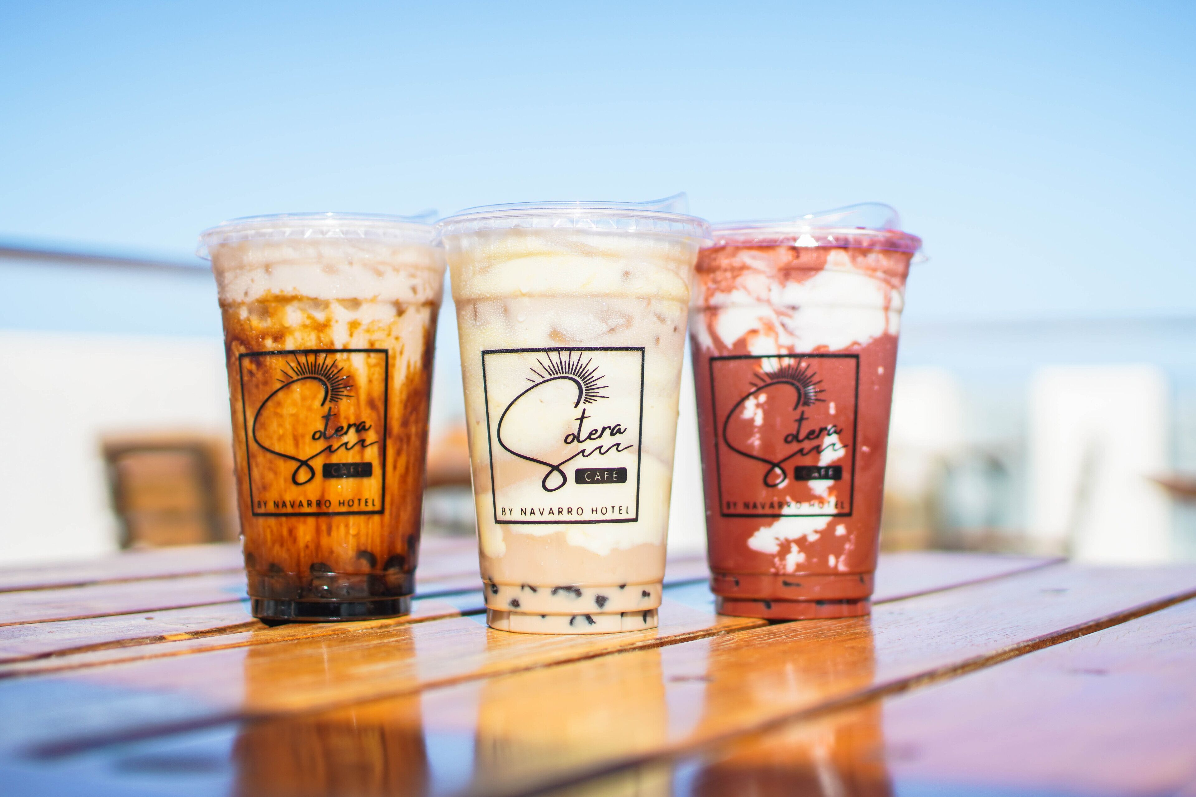 Tres bebidas heladas con etiquetas sobre una mesa de madera.