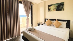 A hotel room with a large bed, a view of the sea, and a painting on the wall. - Navarro Hotel (Malay)