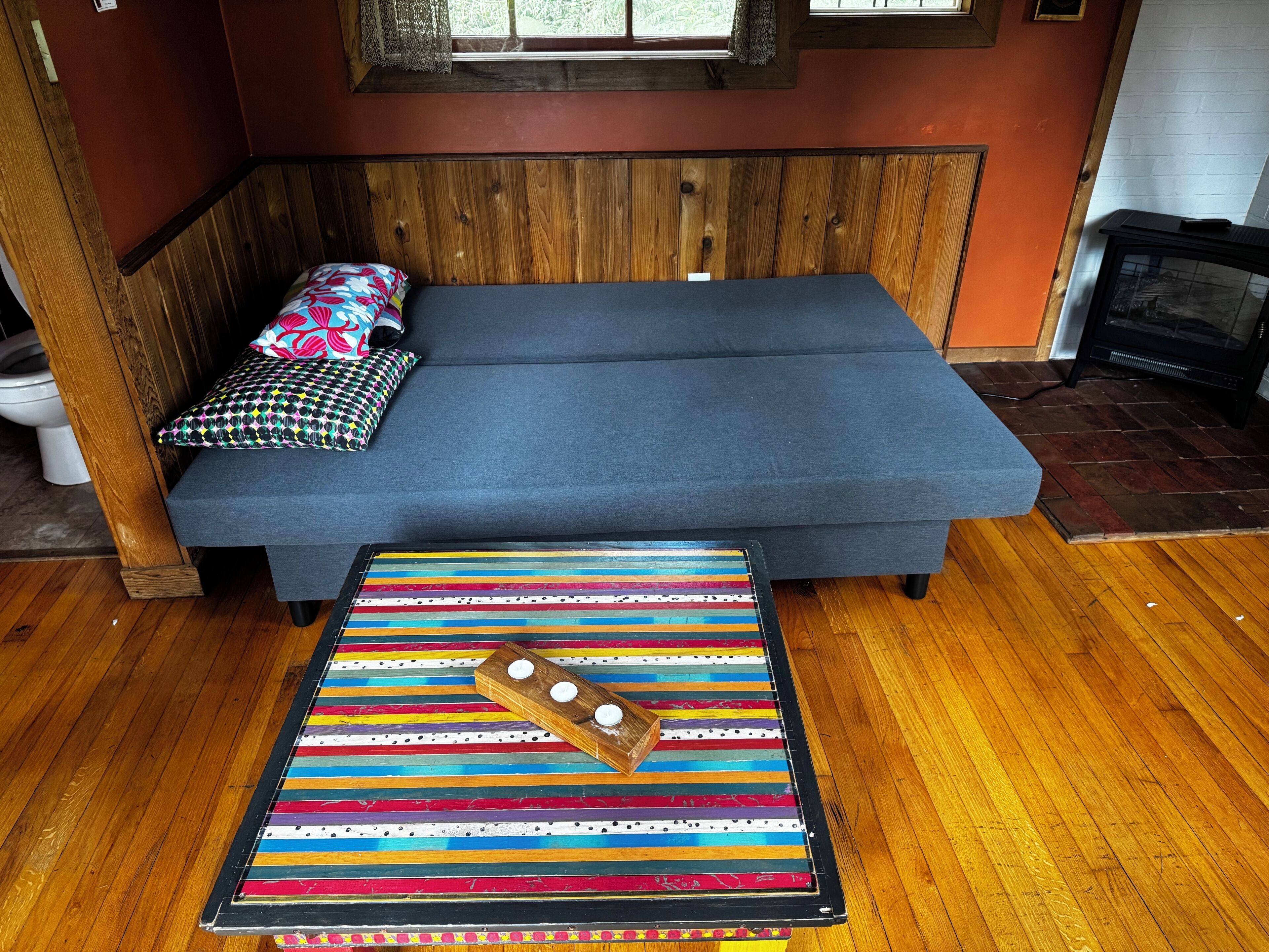 Ein gemütliches Zimmer mit einer hölzernen Bank, einem blauen Sofa und einem gemusterten Teppich.