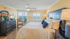 A bedroom with a bed, a dresser, a chair, a ceiling fan, and a window with blinds. - Crystal Sands Tower Unit 1204 - Beachfront (SARASOTA)