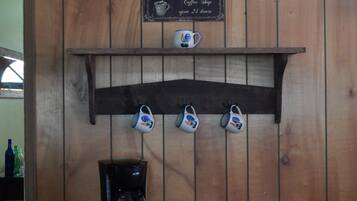 Een bord van een koffiehuis, een plank met mokken en een koffiezetapparaat.
