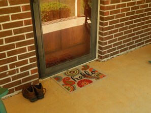 A door with a glass panel, a doormat with 'hello' written on it, and a pair of shoes on the ground beside the door.