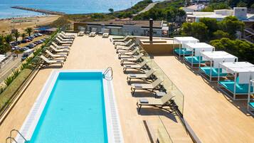 Una piscina en la azotea con tumbonas y vistas a la playa y al océano.