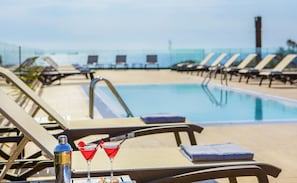 Uma área à beira da piscina com espreguiçadeiras e piscina.