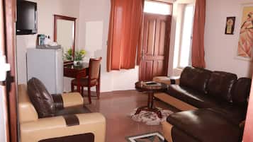 Una sala de estar con un sofá, una mesa de centro, un televisor y un comedor con una silla y una mesa.