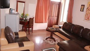 A living room with a sofa, a coffee table, a TV, and a dining area with a table and chairs. - Windy Bay Guest House (Winneba)