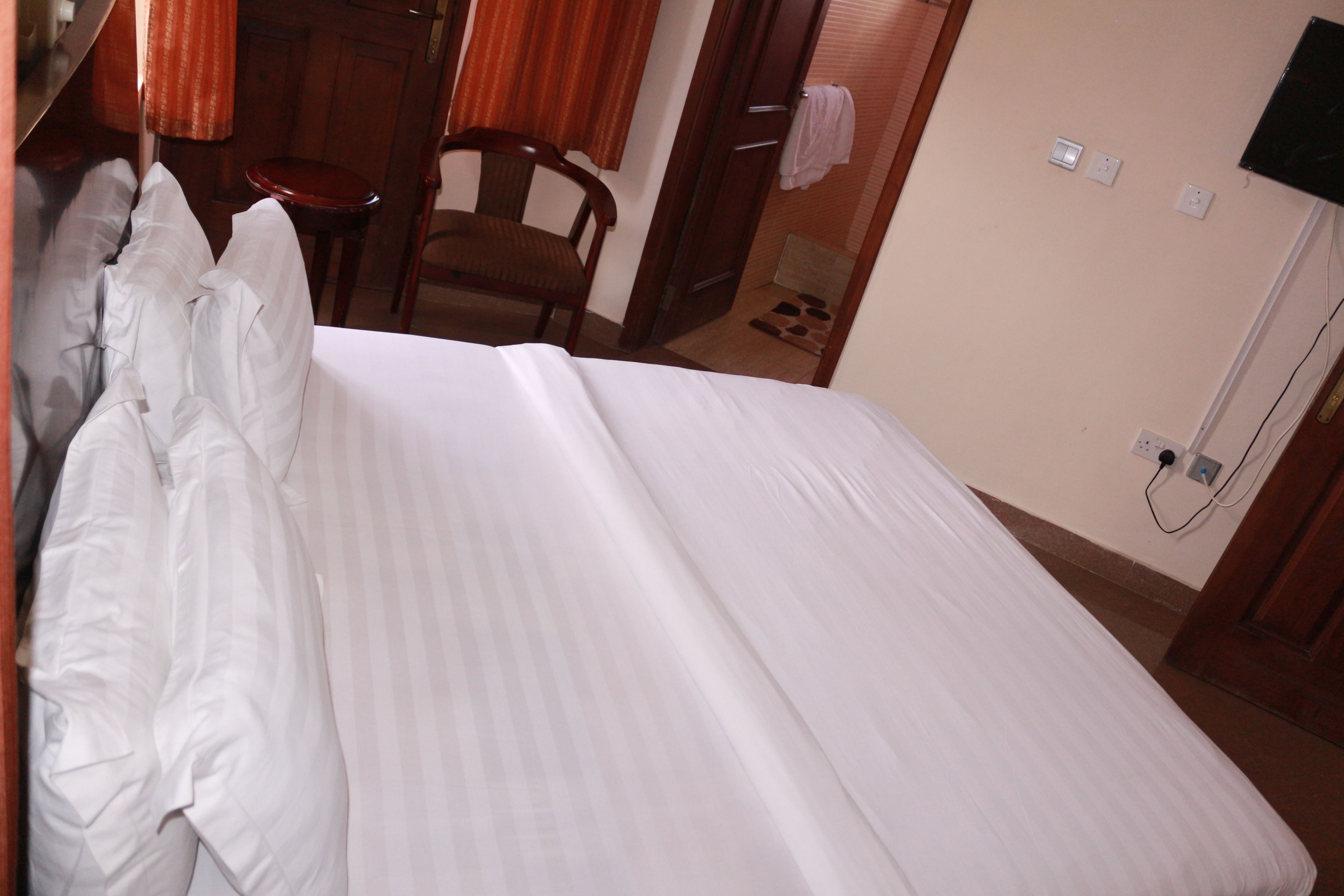 A neatly made bed with white linens in a hotel room.