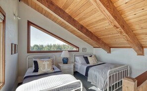 Une chambre avec deux lits, une fenêtre et un plafond en bois.