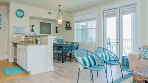 A spacious kitchen with a dining area, featuring a central island, chairs, and a view of the outdoors. - Sea Pointe- The Perfect Beachfront Destination - Brand New Elevator (Galveston)