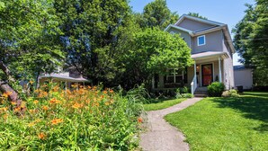 A two-story house with a front porch, a pathway leading to the entrance, and a well-maintained garden with orange flowers. - 3 BR, 2.5 Baths!  GREAT VALUE!!! LOCATION!!!  Highlands, EXPO, Downtown, NULU (Louisville)