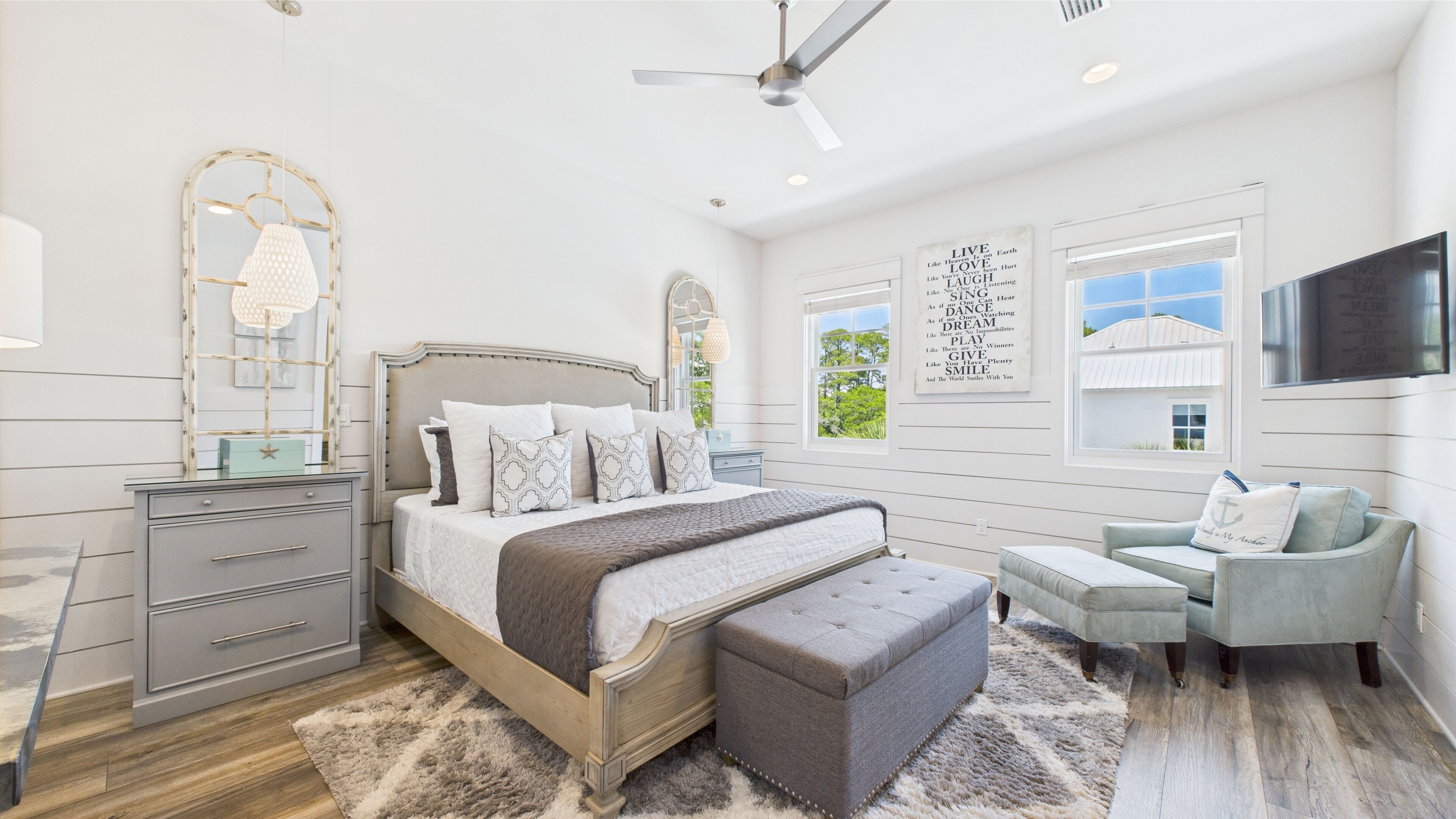 A bedroom with a bed, bedside tables, a dresser, a chair, and a ceiling fan.