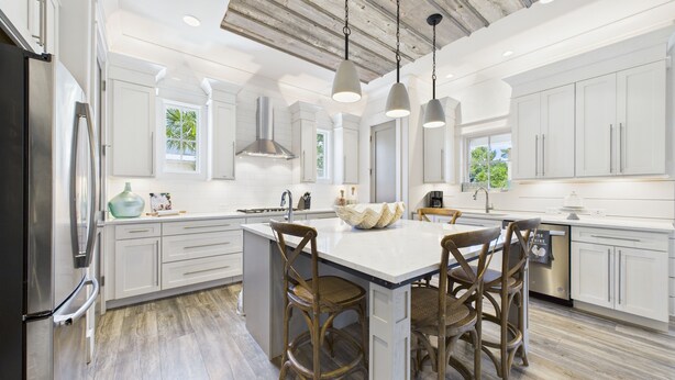 A modern kitchen with white cabinetry, a central island with bar stools, pendant lighting, and a stainless steel refrigerator. - 4 Bedroom Grayton Luxury-Elevator-Sleeps 12- Private beach access with set-up (Santa Rosa Beach)