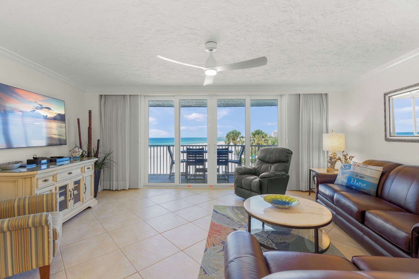 A living room with a large window, a ceiling fan, a sofa, a coffee table, and a television.
