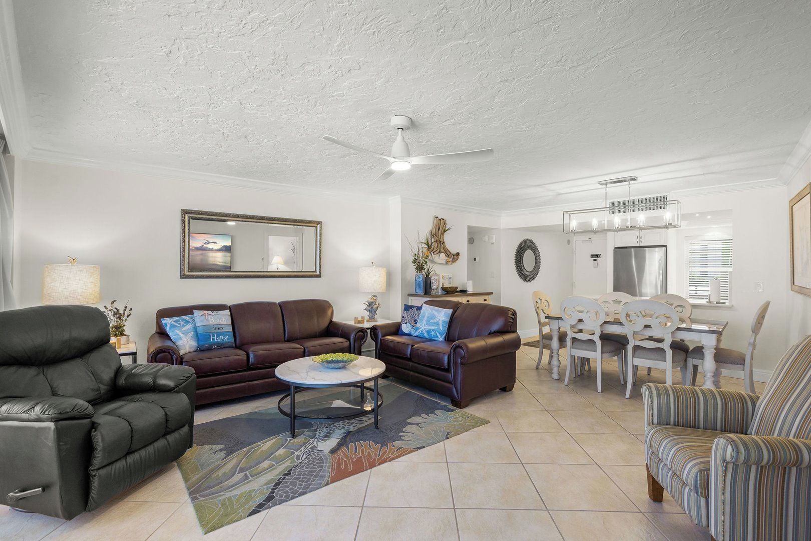 A living room with a sofa, armchair, coffee table, and dining area with chairs and a table.