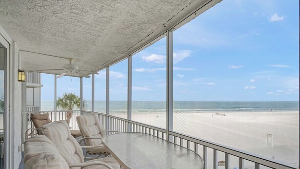 A balcony with a glass table and chairs, overlooking a beach. - Crystal Sands Tower Unit 305 - Beachfront (Sarasota)