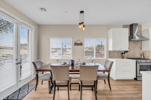 A dining area with a wooden table, four chairs, and a hanging light fixture.