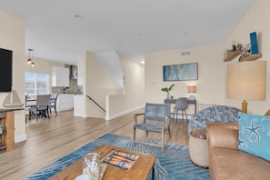 A spacious living area with a dining table, a sofa, and a kitchen in the background.
