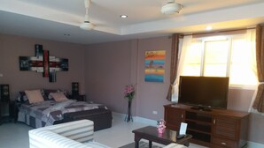 A modern living room with a bed, sofa, TV, and artwork on the walls. - Studio Deluxe Avec Services Hôteliers - Adults Only (Rawai)