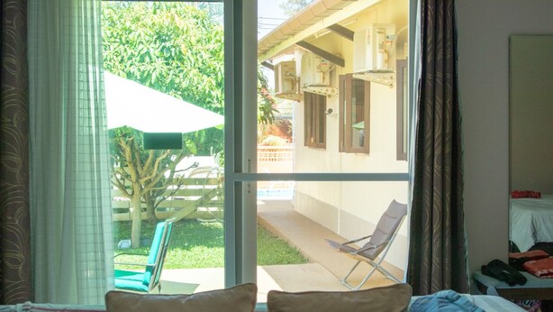 A room with a sliding glass door leading to a patio with a chair and a table. - Studio Deluxe Avec Services Hôteliers - Adults Only (Rawai)