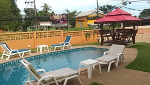 A backyard with a swimming pool, lounge chairs, a gazebo, and a fenced area. - Studio Deluxe Avec Services Hôteliers - Adults Only (Rawai)