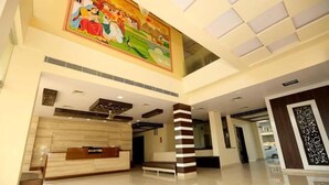 A hotel reception area with a reception desk, a large mural on the ceiling, and a modern interior design. - Rock Star Hotel (Pushkar)