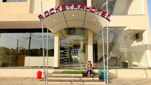 The exterior of the Rockstar Hotel with a clear entrance, a person sitting on the steps, and a well-maintained facade. - Rock Star Hotel (Pushkar)