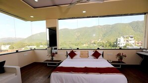 A bedroom with a large bed, a white sofa, and a view of mountains. - Rock Star Hotel (Pushkar)
