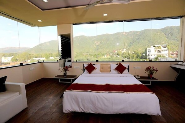 A bedroom with a large bed, a white sofa, and a view of mountains.