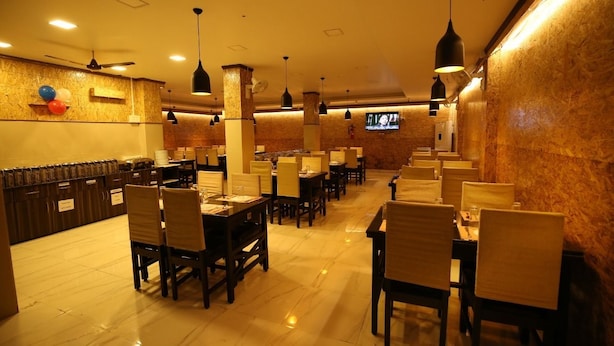 Um restaurante com várias mesas e cadeiras, uma televisão na parede e um ventilador de teto.