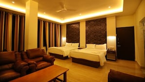 Quarto de hotel com duas camas, um sofá, uma mesa e um ventilador de teto.
