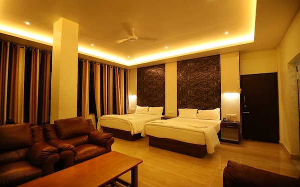 Quarto de hotel com duas camas, um sofá, uma mesa e um ventilador de teto.