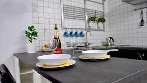 Uma cozinha moderna com paredes azulejadas brancas, bancada preta e janela com persianas.