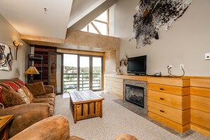 Relax in this inviting living area with a fireplace, large windows, and comfortable seating.