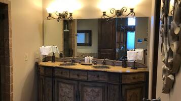 A bathroom with a large mirror, two sinks, and a towel rack.