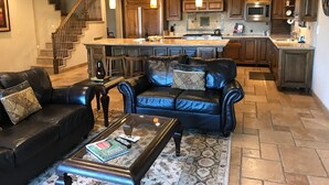 Un salon spacieux, doté d’un canapé en cuir, d’une table basse et d’un escalier menant à l’étage supérieur.