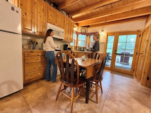 Una cucina in legno con zona pranzo, caratterizzata da mobili in legno, un frigorifero, un forno a microonde e un tavolo con sedie.