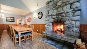 Un comedor con chimenea de piedra, mesa de madera y sillas.
