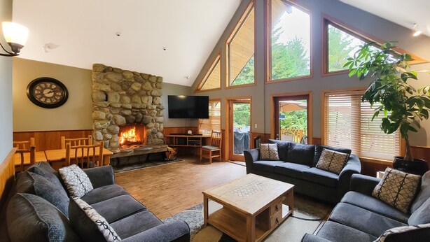 Una sala acogedora con chimenea de piedra, asientos cómodos y ventanas amplias.