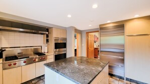 Una cocina moderna con electrodomésticos de acero inoxidable, encimera de granito y vistas al área de comedor.