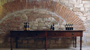 Una mesa de madera con botellas y vasos frente a una pared de piedra.